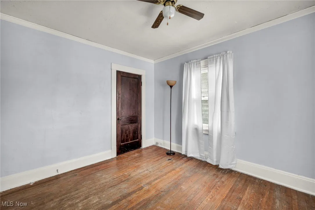 Empty room featuring hardwood / wood-style floors, ornamental molding, and ceiling fan
