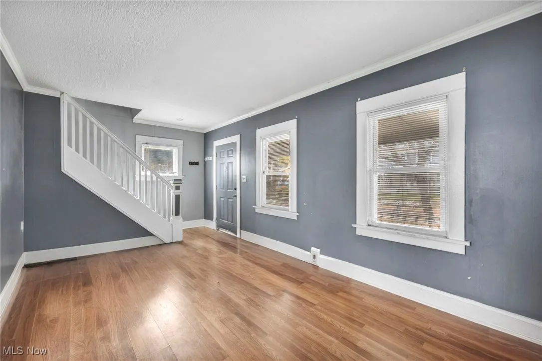 Entryway featuring crown molding, stairway, wood finished floors, and a textured ceiling