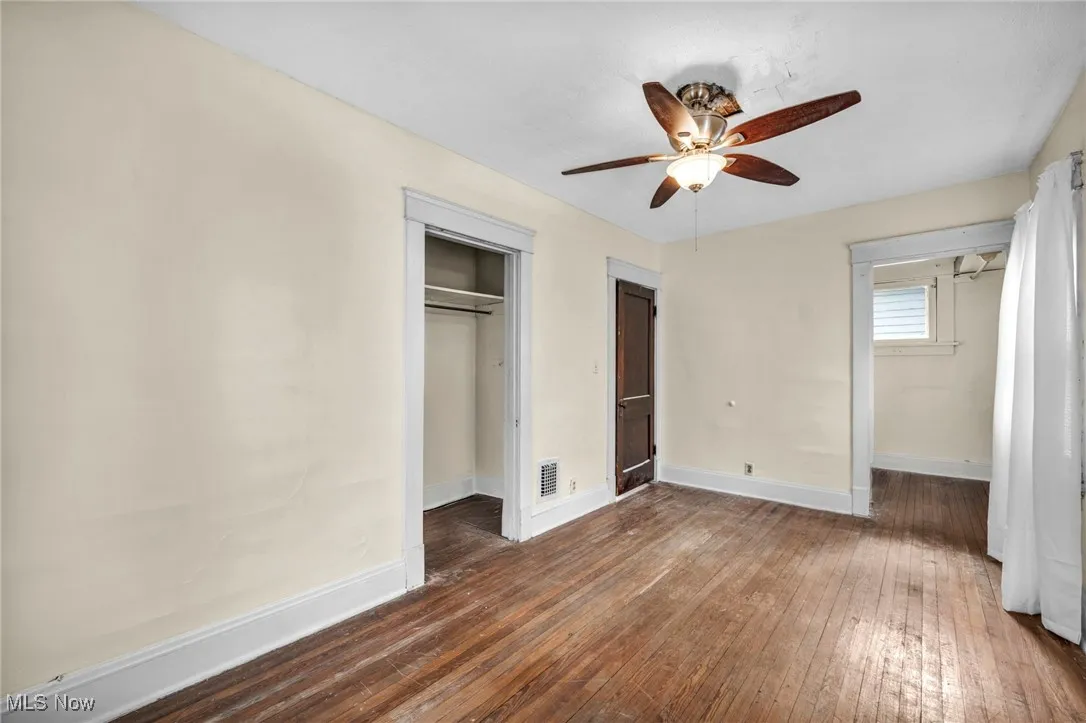 Unfurnished bedroom featuring dark wood-style floors, a closet, and a ceiling fan