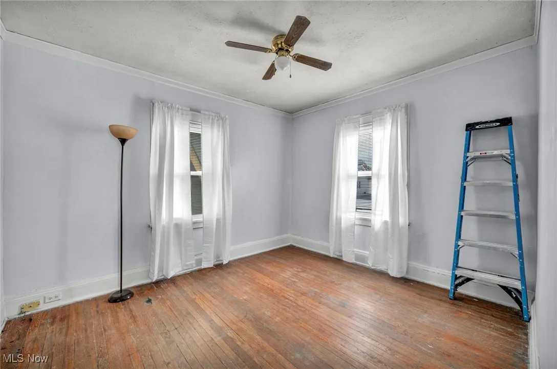 Unfurnished room featuring wood-type flooring, ornamental molding, a textured ceiling, and ceiling fan