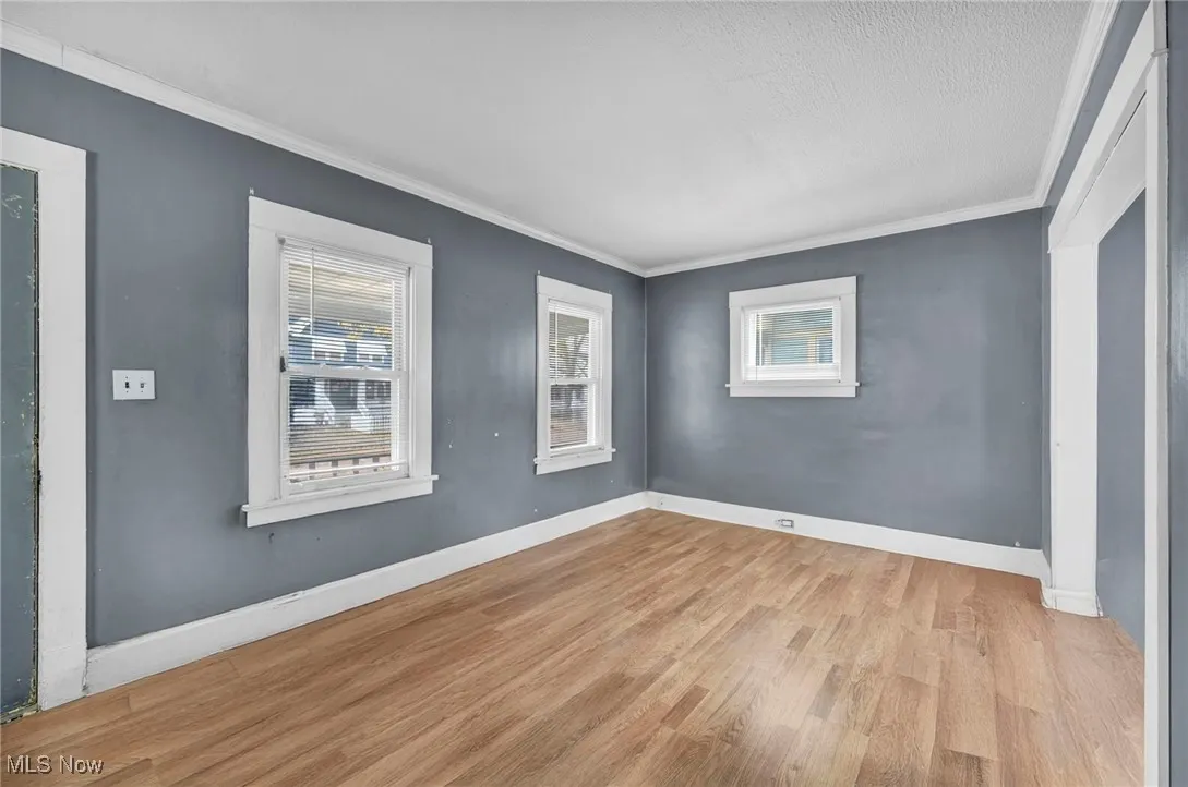 Empty room with light wood-style floors and crown molding