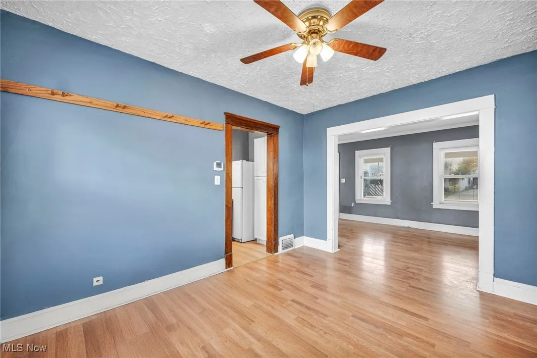 Empty room featuring a textured ceiling, wood finished floors, and a ceiling fan