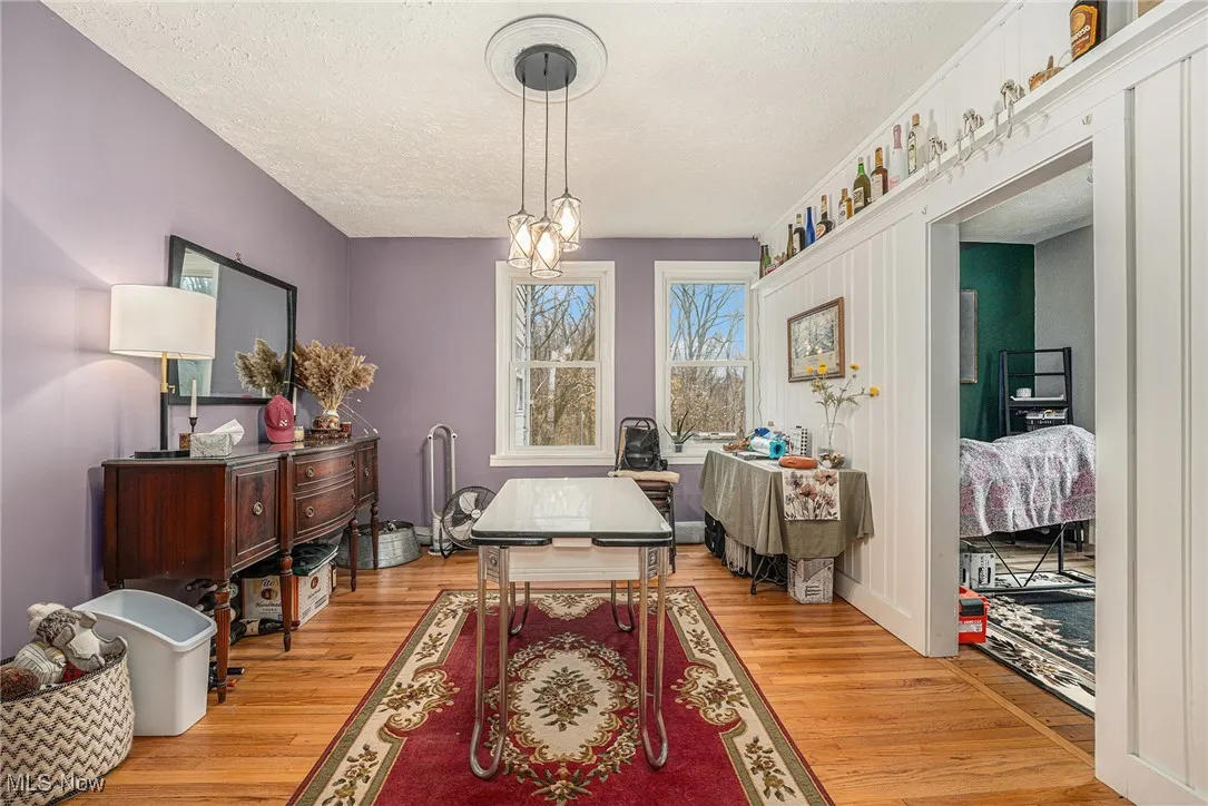 Dining space featuring light wood-type flooring, a textured ceiling, and a chandelier