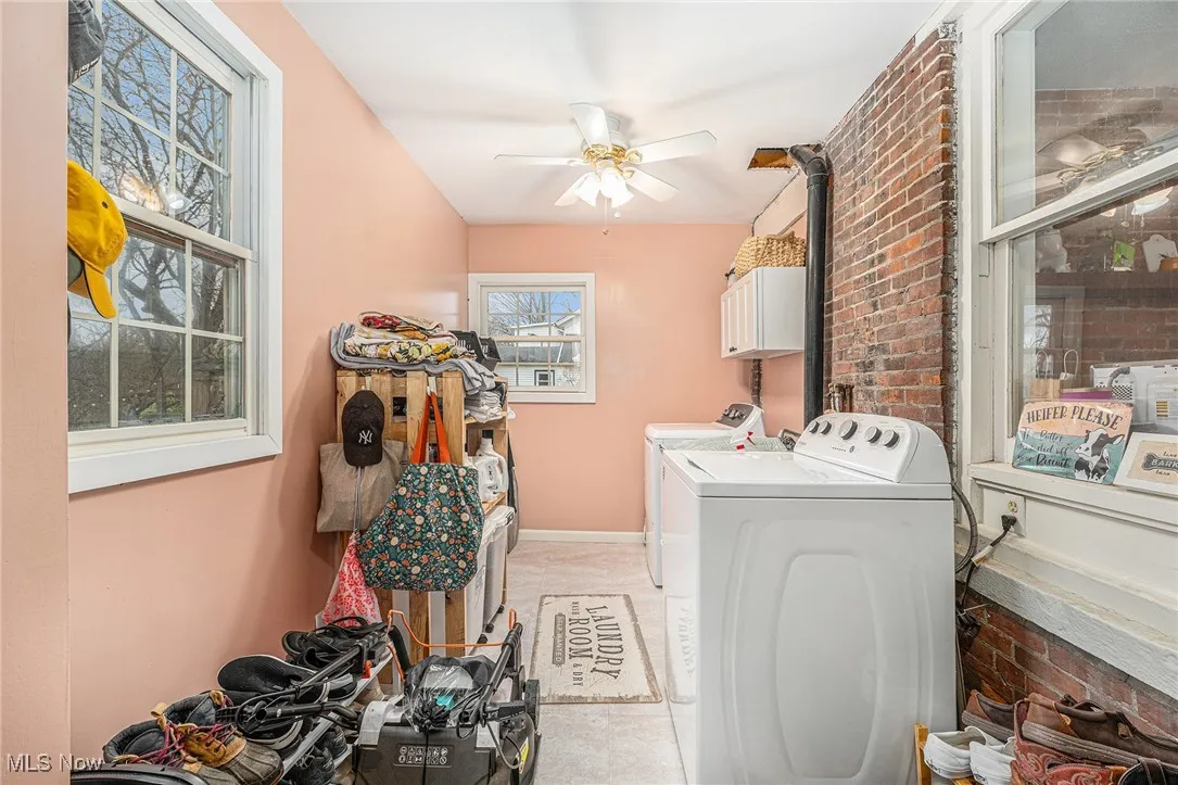 Washroom with brick wall, separate washer and dryer, light tile patterned flooring, and cabinet space