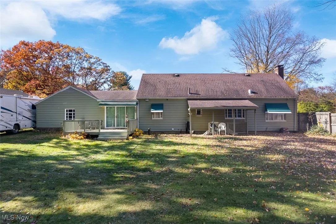 Rear view of property featuring a deck, a lawn, and a chimney