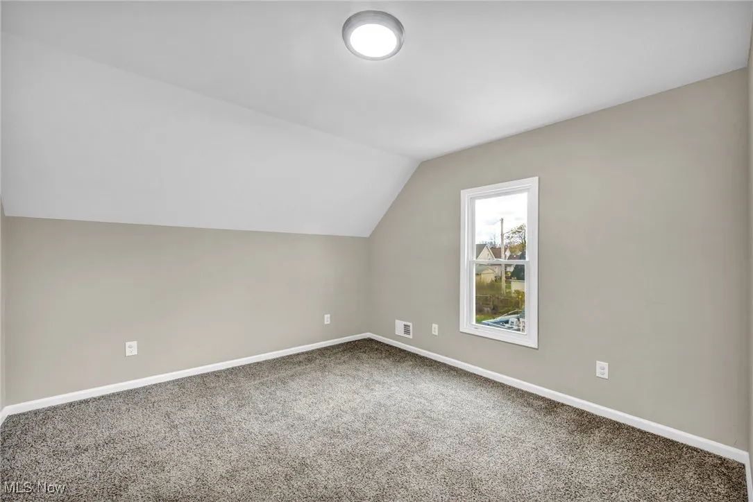 Additional living space featuring vaulted ceiling and carpet flooring