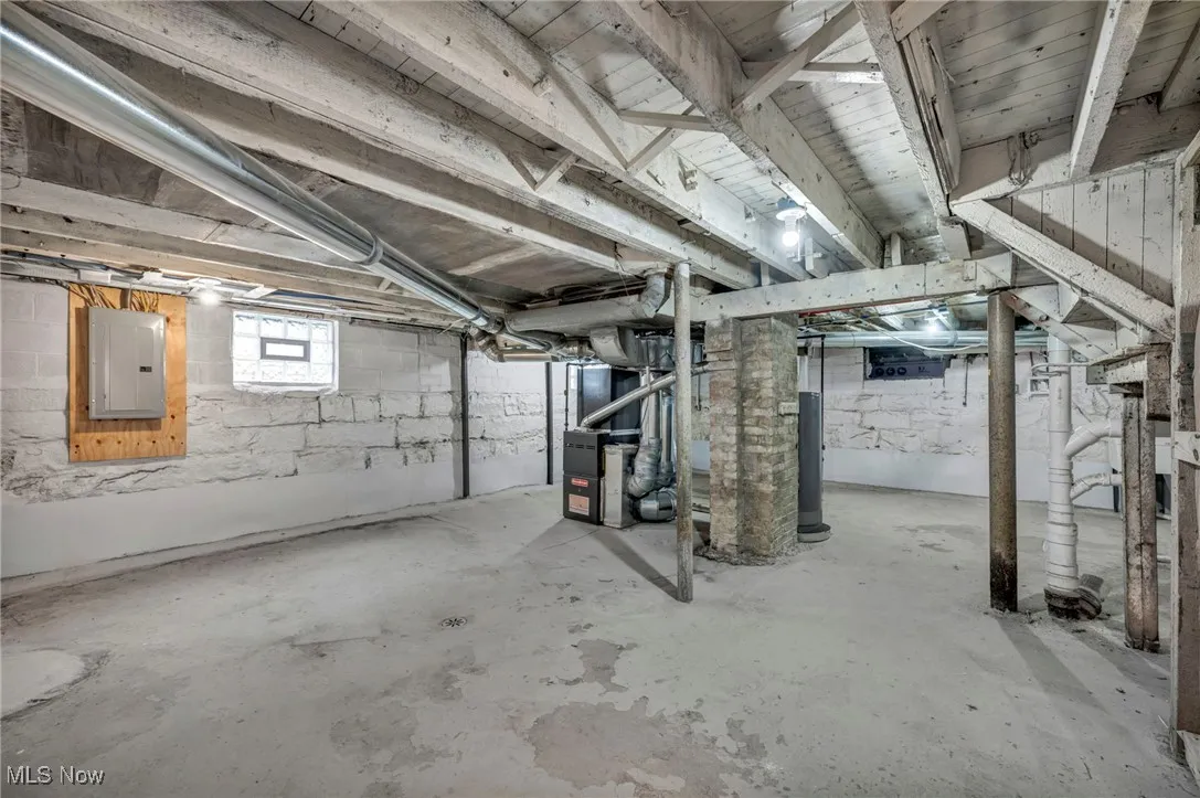 Below grade area featuring electric panel, heating unit, and water heater