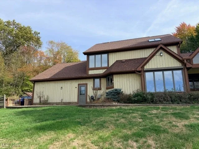Rear view of property featuring roof with shingles and a yard
