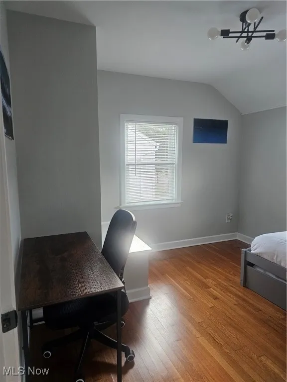 Office space featuring light wood finished floors and vaulted ceiling