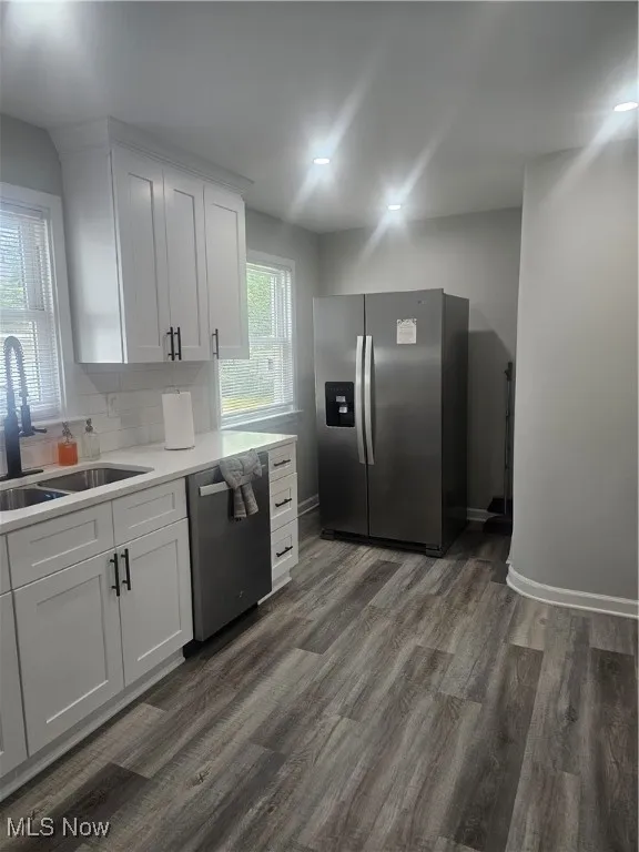 Kitchen featuring white cabinets, stainless steel fridge, dishwasher, and tasteful backsplash