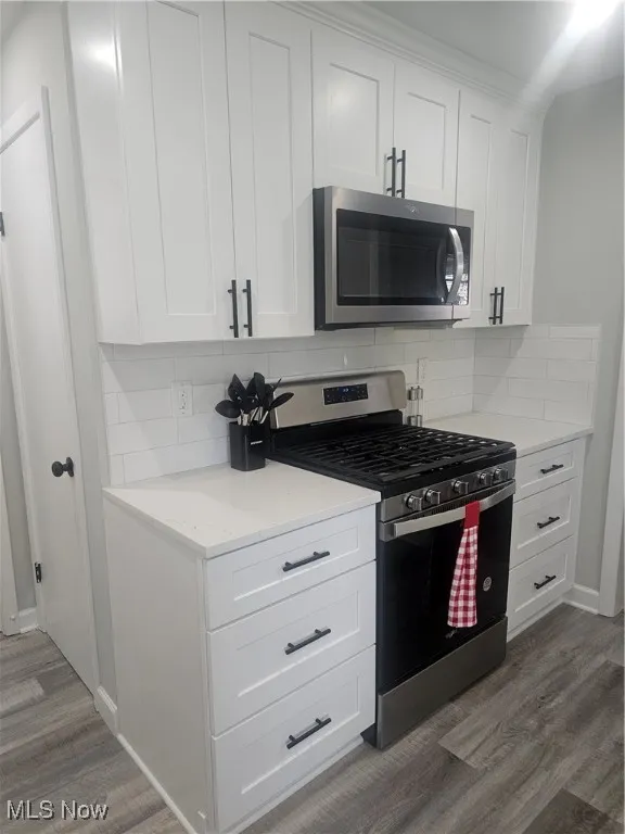 Kitchen featuring stainless steel appliances, white cabinets, and dark wood-style flooring