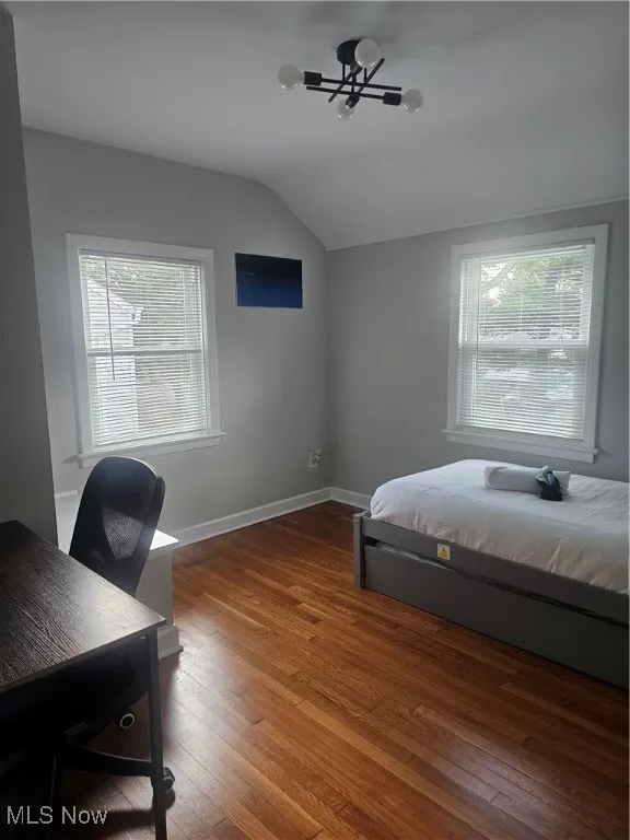 Bedroom with wood-type flooring, vaulted ceiling, and a desk