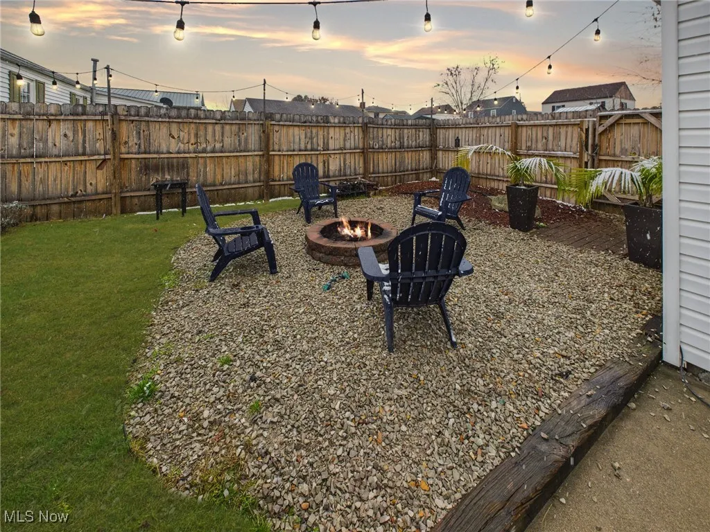 Yard at dusk with a fenced backyard, a patio, and a fire pit