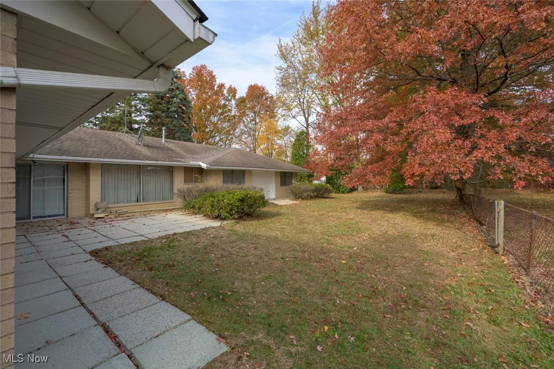 View of patio, side garage entrance and back yard.