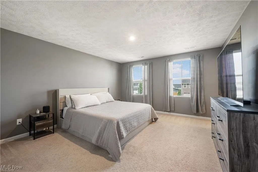 Bedroom with light colored carpet and a textured ceiling