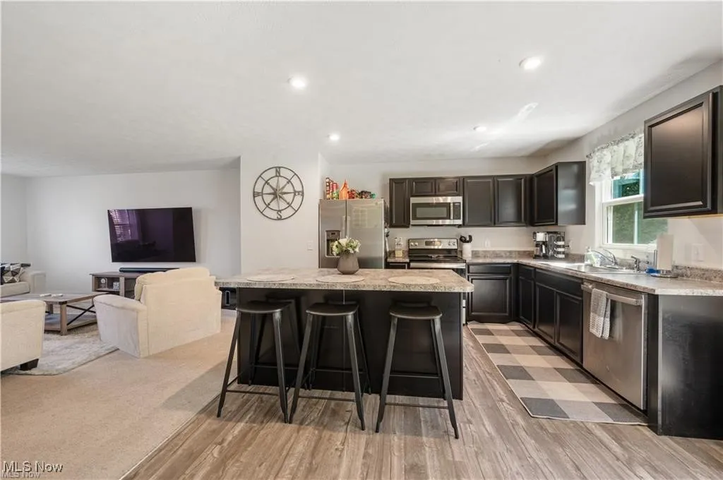 Kitchen featuring stainless steel appliances, a kitchen breakfast bar, a center island, recessed lighting, and light wood finished floors