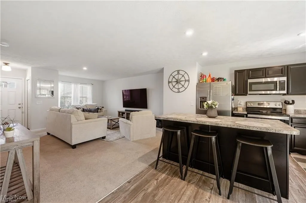 Kitchen with dark brown cabinetry, appliances with stainless steel finishes, a breakfast bar, recessed lighting, and a center island