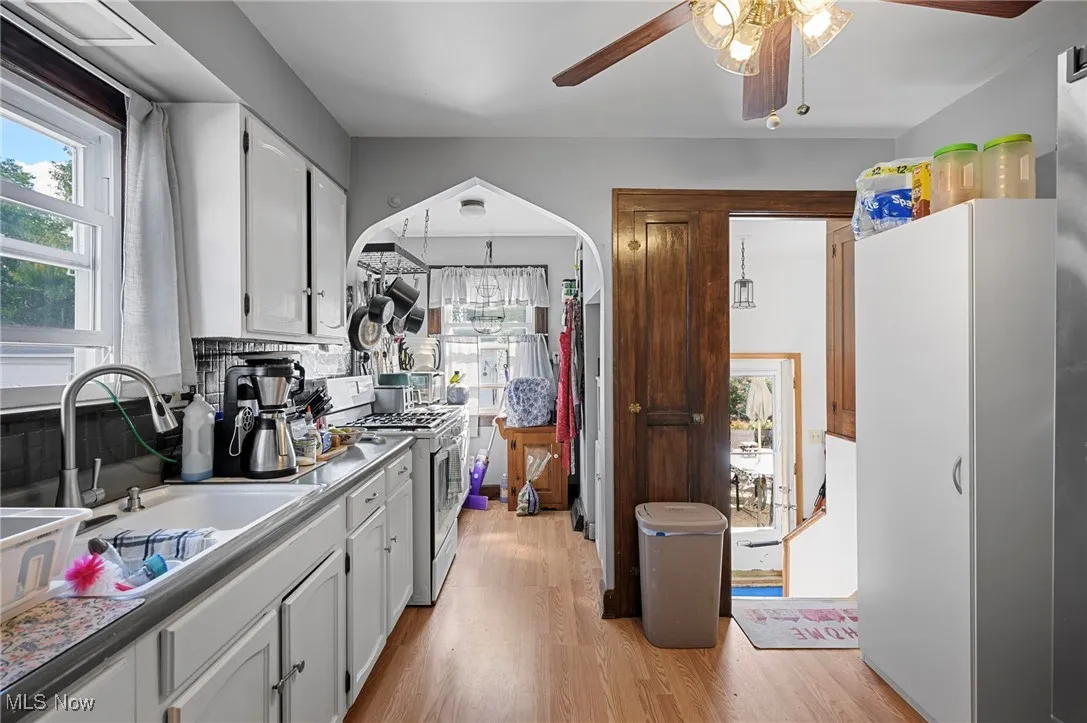 Kitchen with white cabinetry, light wood finished floors, healthy amount of natural light, and range with gas cooktop
