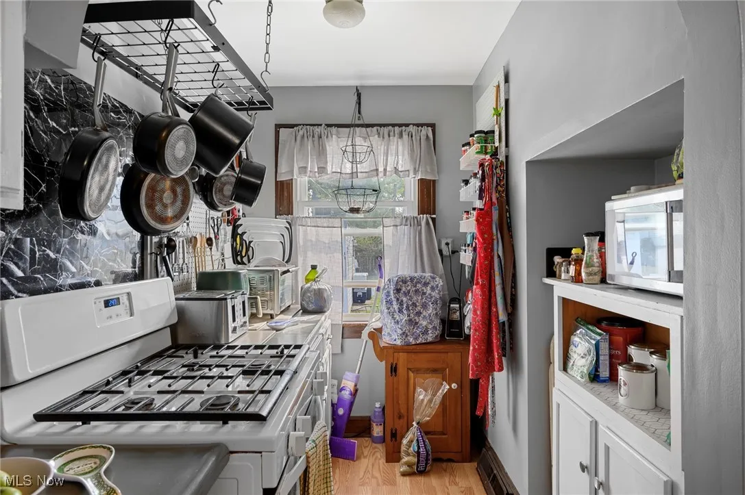 Kitchen with gas range gas stove, light wood-type flooring, white cabinetry, and light countertops