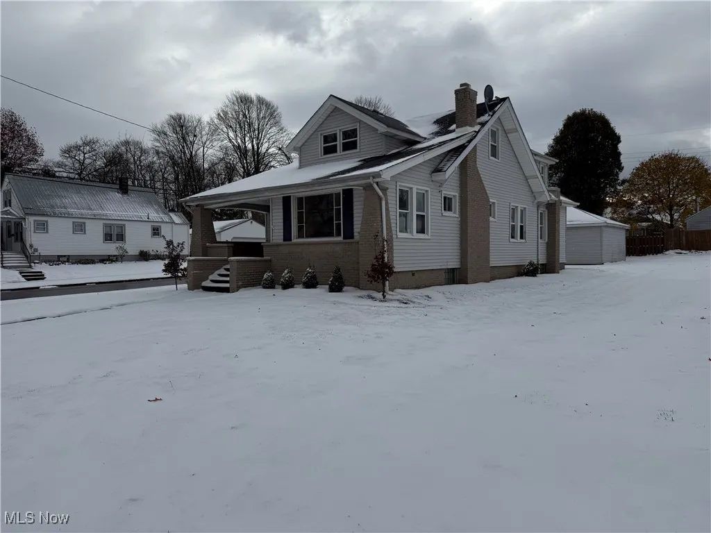 Bungalow with brick siding, a porch, a chimney, and an outdoor structure