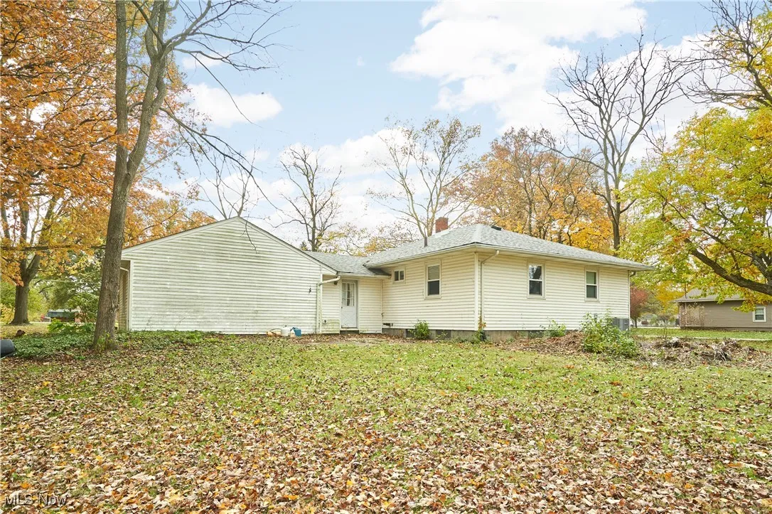 Rear view of house featuring a chimney and a lawn