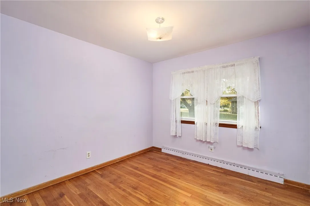 Unfurnished room featuring baseboard heating and light wood-style floors