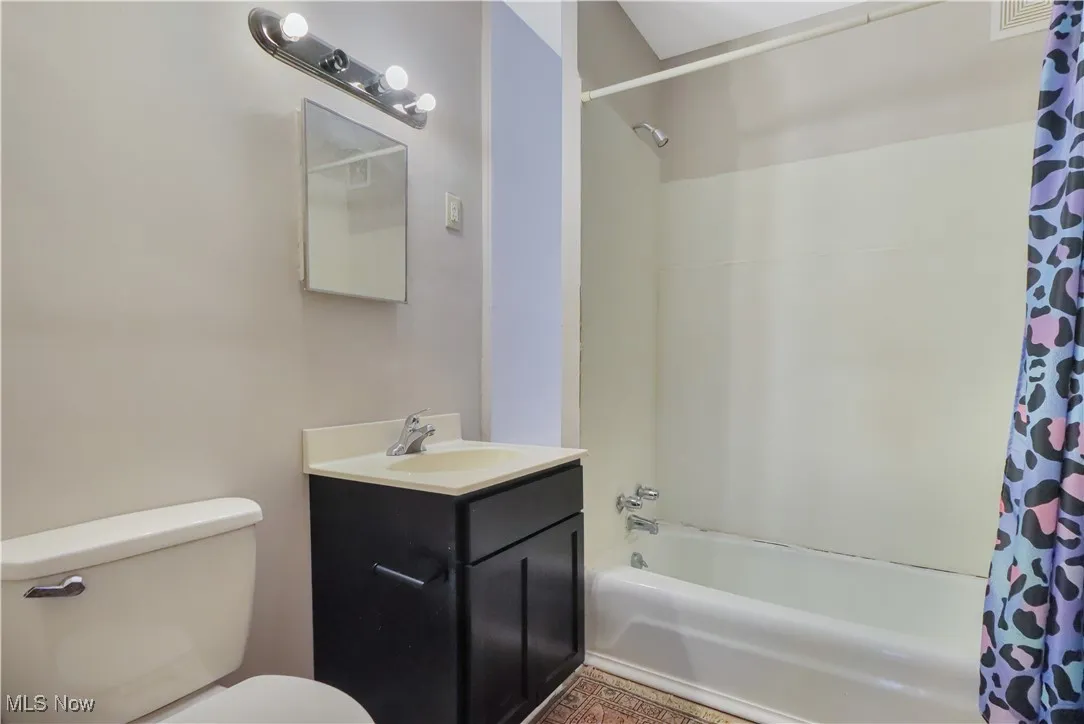 Bathroom with shower / bath combo with shower curtain and vanity