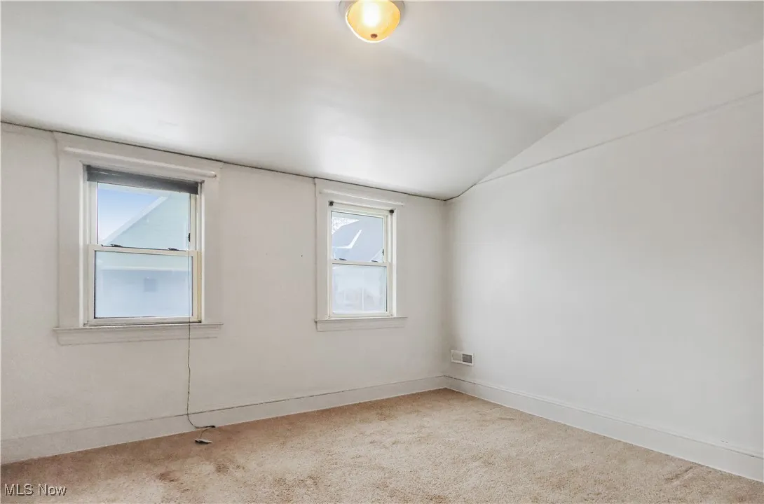 Spare room featuring vaulted ceiling and carpet