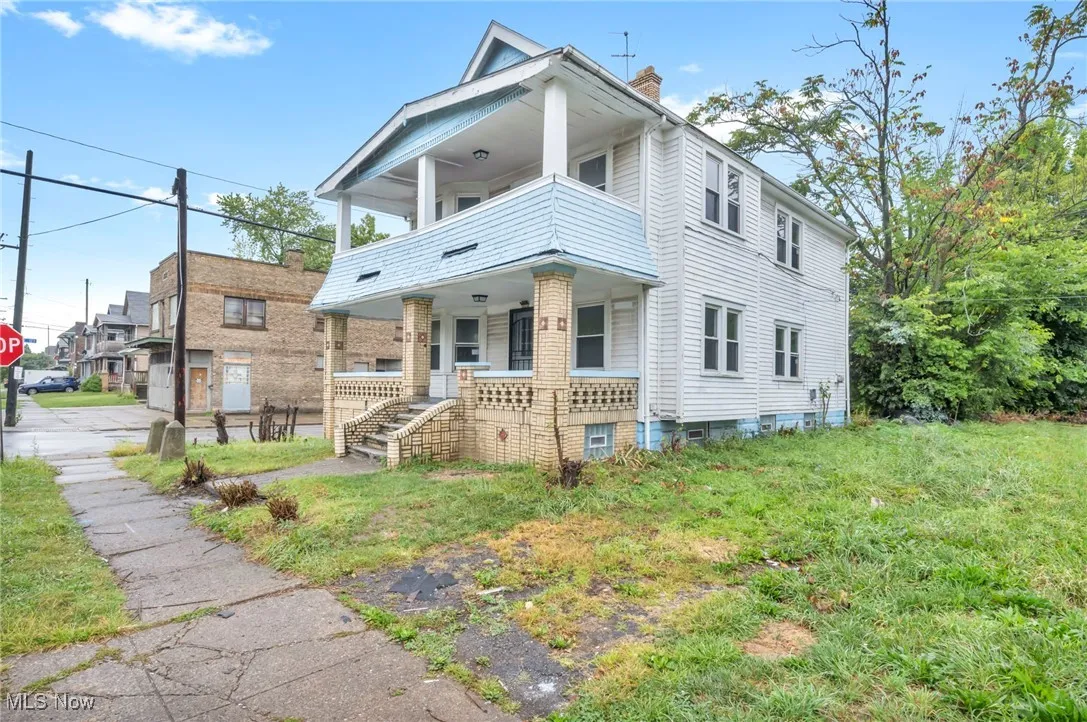 View of front of home with a chimney, covered porch, a balcony, and a front lawn