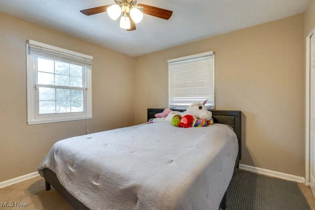 Carpeted bedroom featuring baseboards and ceiling fan