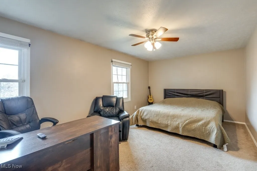 Bedroom featuring light colored carpet, an office area, and ceiling fan