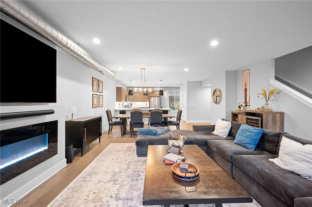 Living room with a fireplace, recessed lighting, light wood-style floors, and beverage cooler