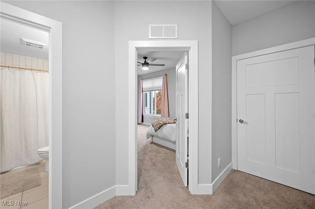 Hallway featuring light carpet and baseboards