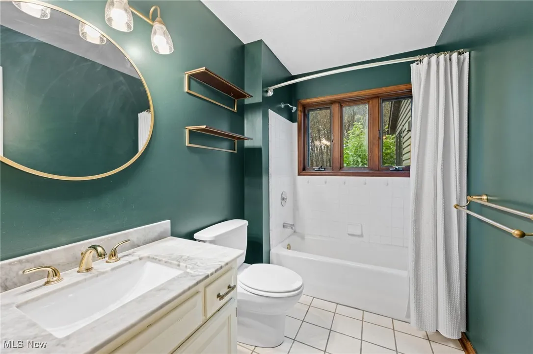 Full bath with light tile patterned flooring, shower / bath combo, and vanity