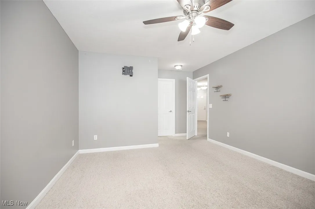 Empty room with light colored carpet and ceiling fan