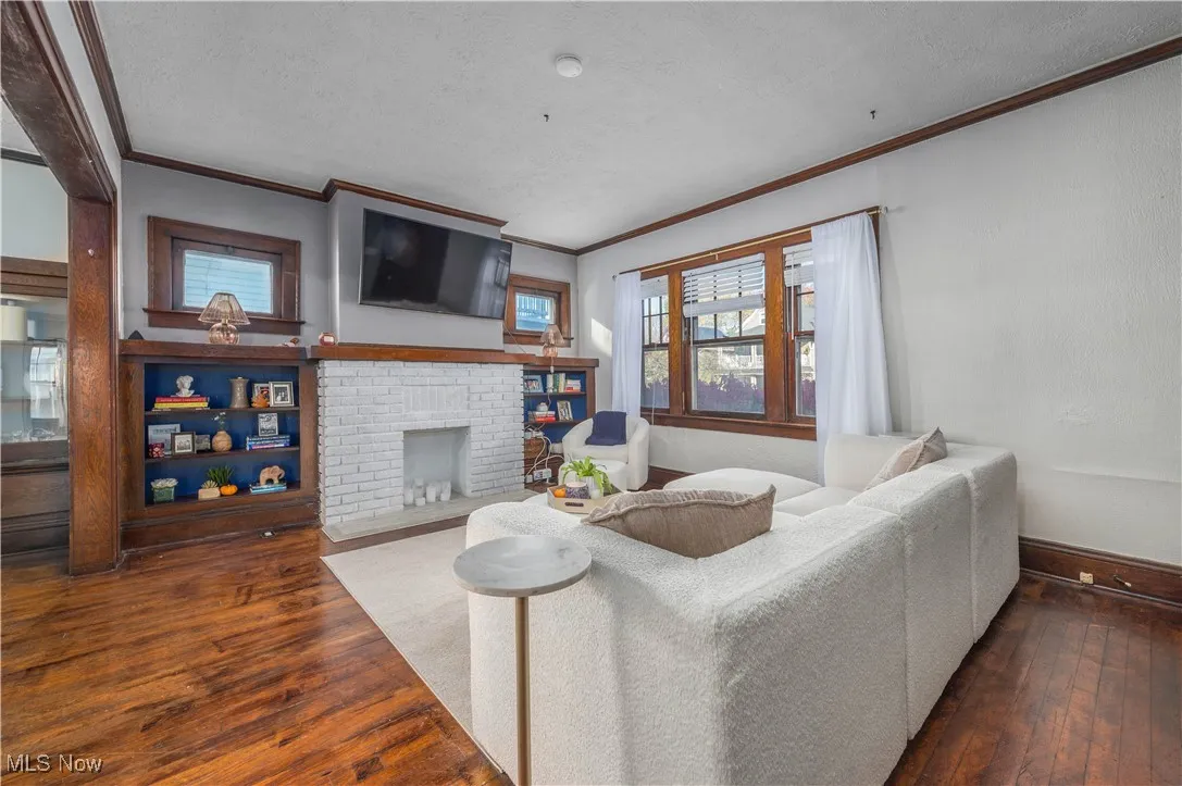 Living area with dark wood-style floors, crown molding, a textured ceiling, and a fireplace