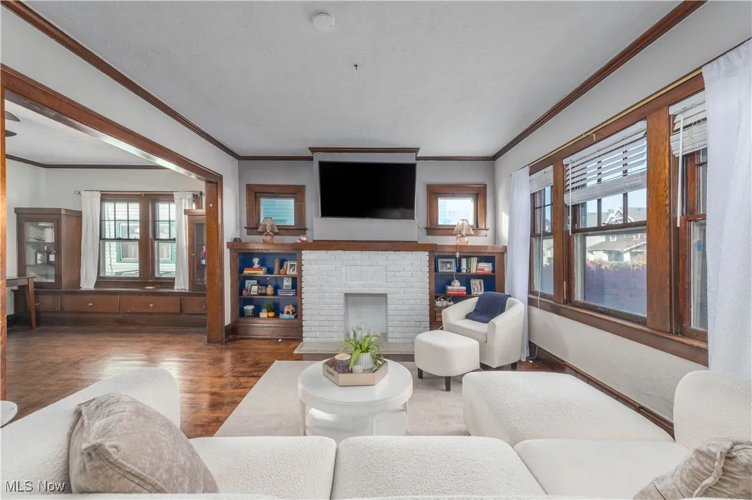 Living area with a fireplace, crown molding, and wood finished floors