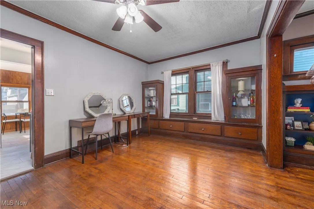 Office space or dining room area featuring hardwood / wood-style floors, ornamental molding, a textured ceiling, and ceiling fan