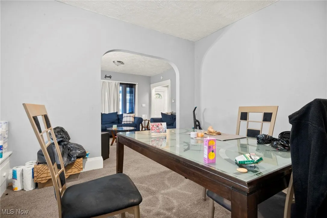 Office area featuring carpet floors, a textured ceiling, and arched walkways