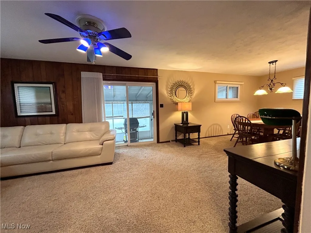 Carpeted family room with healthy amount of natural light and wood walls