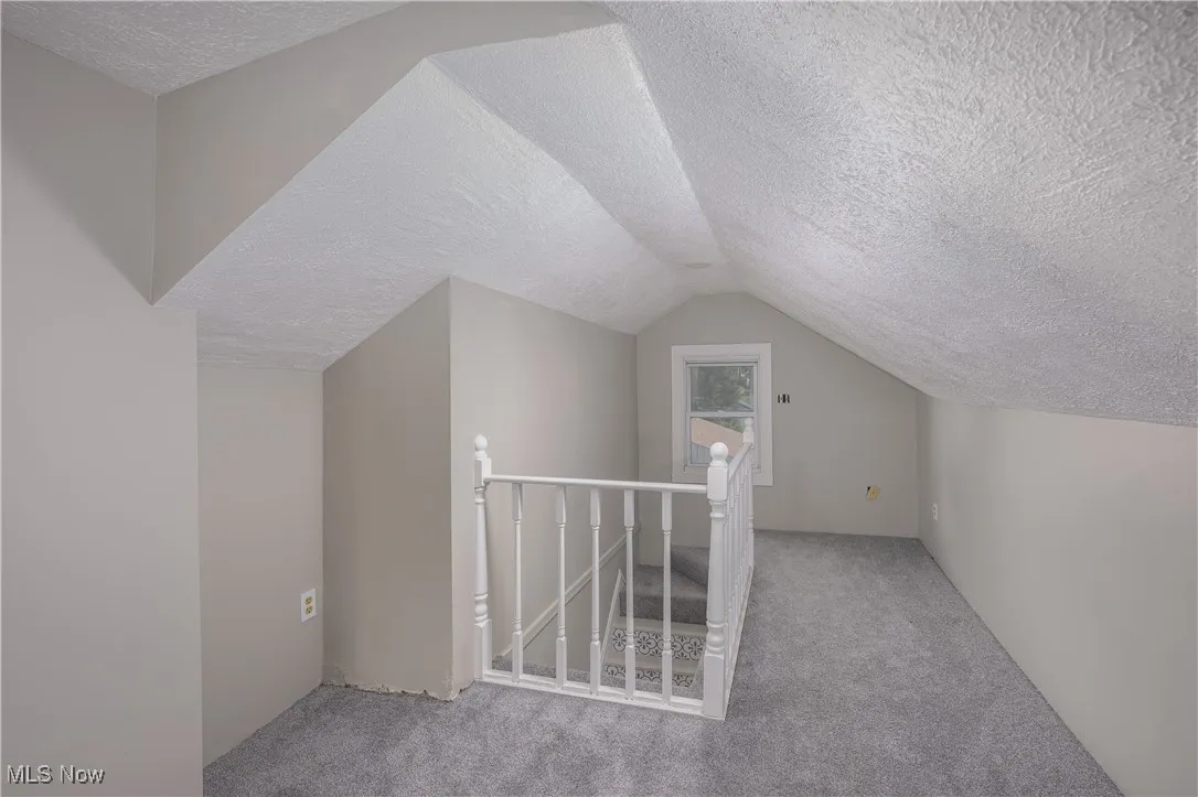 Bedroom featuring a textured ceiling, carpet flooring, and lofted ceiling