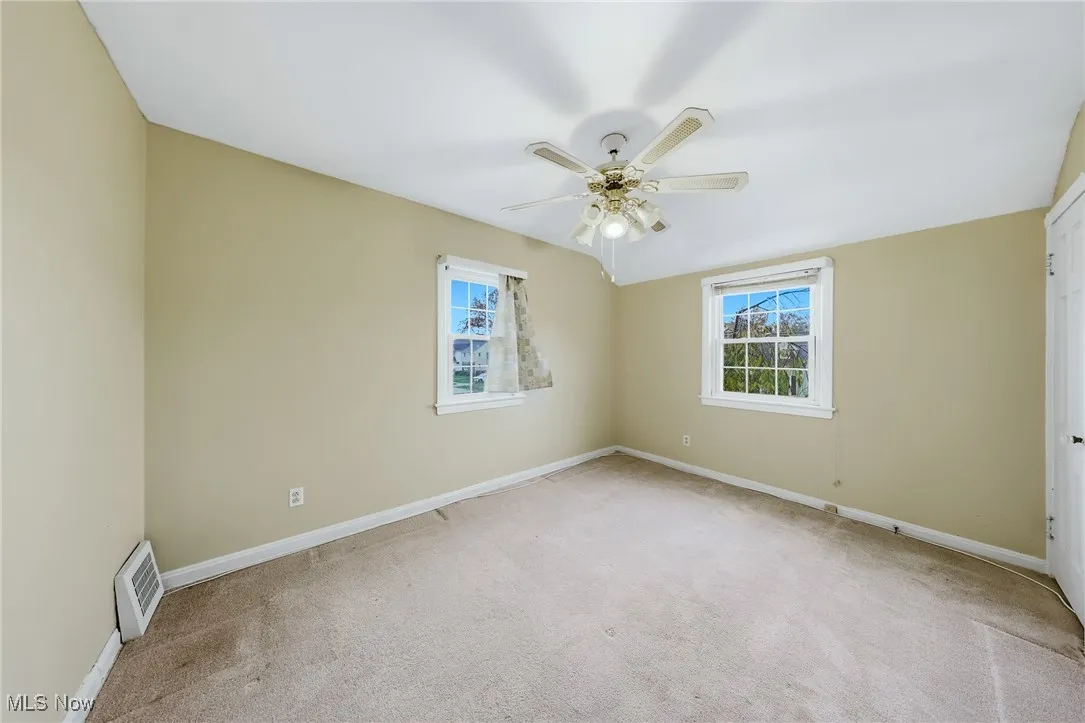 Carpeted empty room with healthy amount of natural light and a ceiling fan