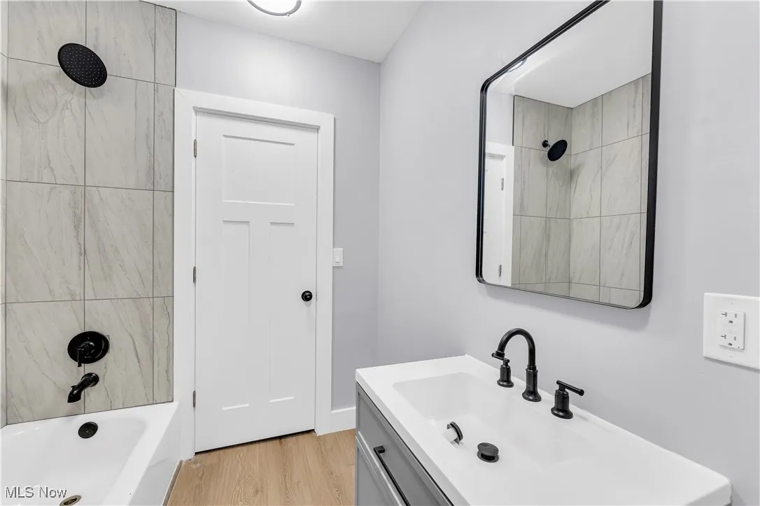 Full bath featuring vanity, light wood-type flooring, and shower / tub combination