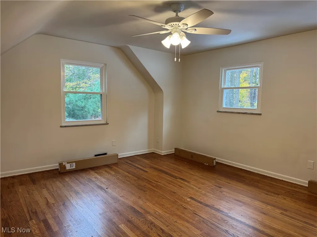 Bonus room with dark wood-style floors, a ceiling fan, and vaulted ceiling
