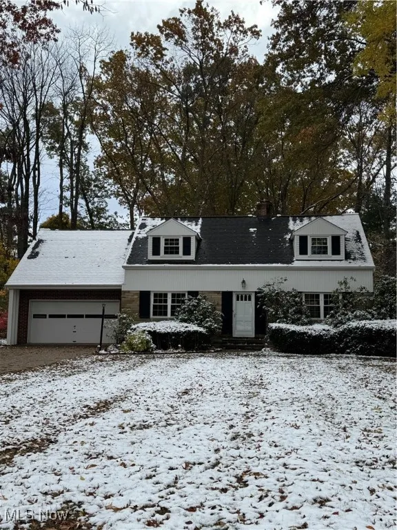 Cape cod house with a chimney and an attached garage