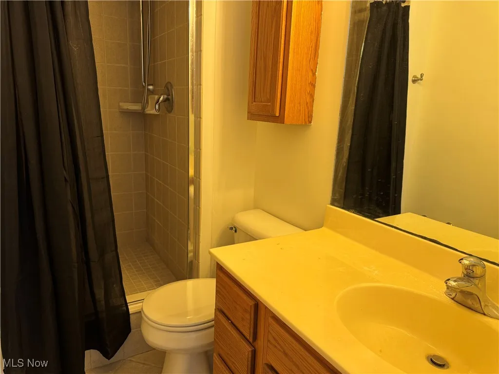 Full bath featuring a stall shower, vanity, and light tile patterned floors