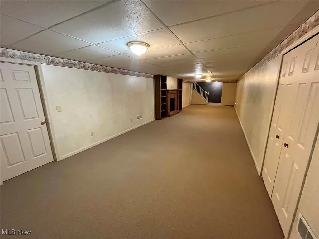 Finished below grade area featuring a drop ceiling and carpet flooring