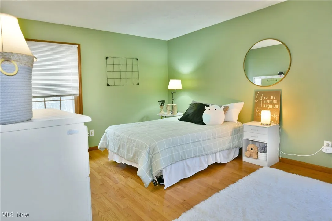 Bedroom with light wood-type flooring and white refrigerator