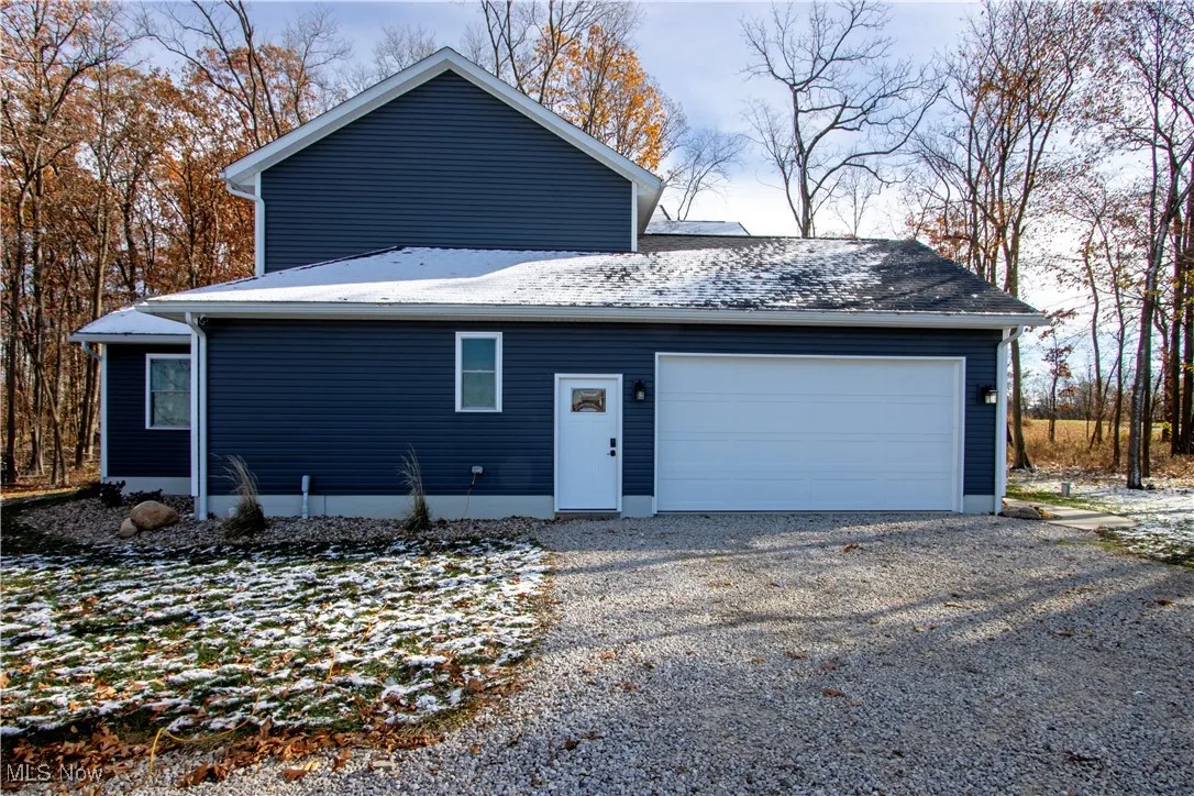 View of home's exterior featuring gravel driveway and an attached garage