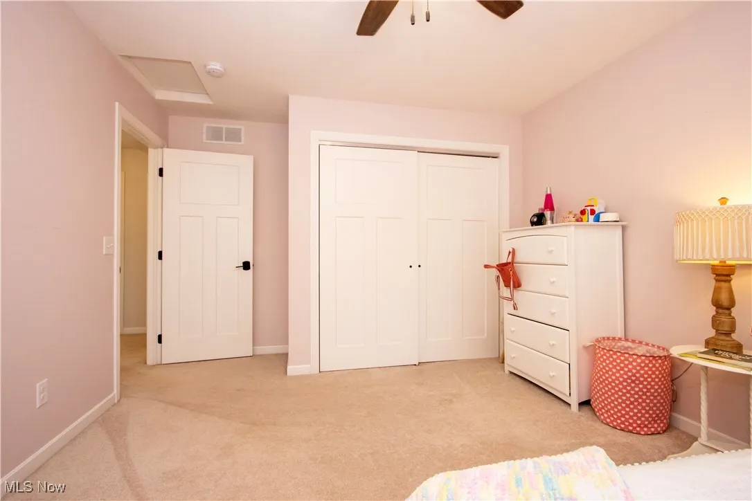 Bedroom with light colored carpet, a closet, attic access, and ceiling fan